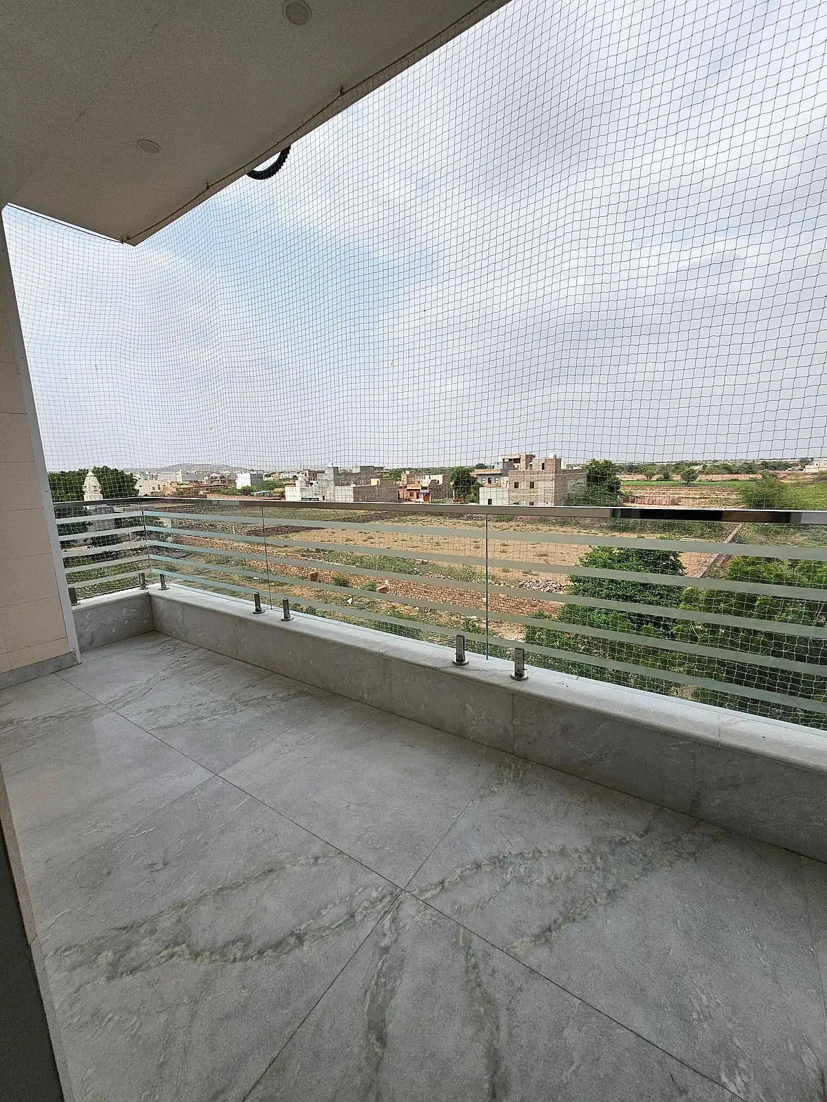 Wider view across the open balcony, protective mesh and surrounding neighbourhood