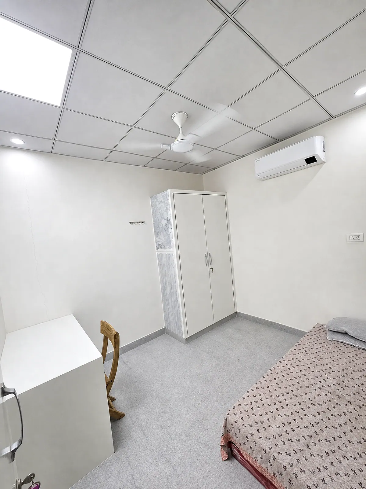 Furnished room with a bed, wardrobe, study desk, ceiling fan and split air conditioner