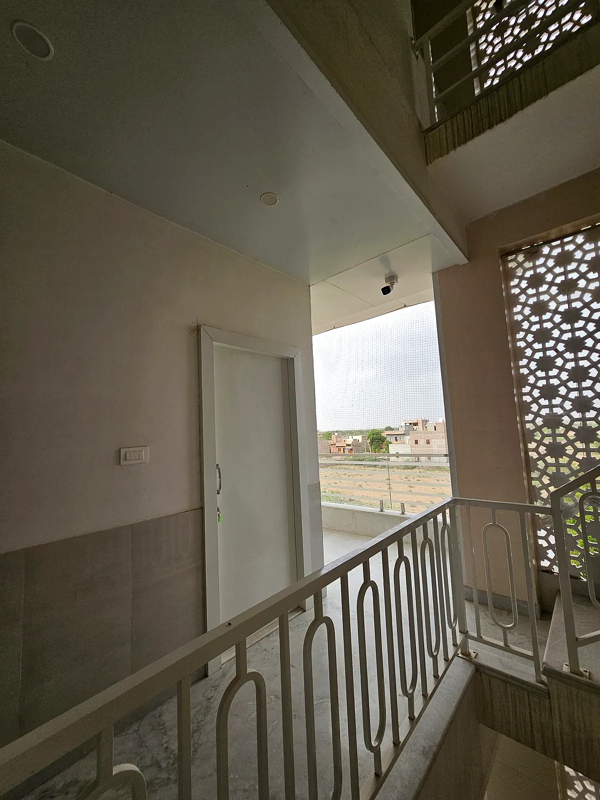 Stair landing with railing, decorative ventilation screen and an open neighbourhood view