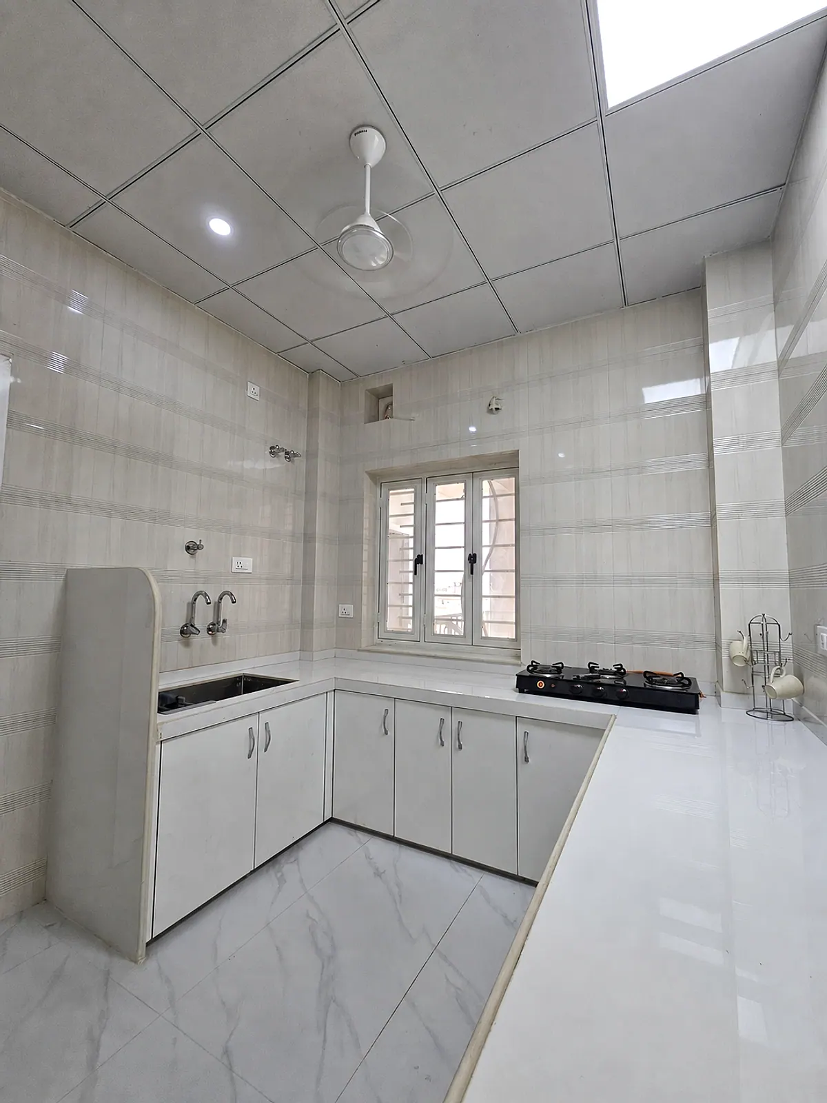 Bright shared kitchen with U-shaped counter, cabinets, sink, window and cooking units