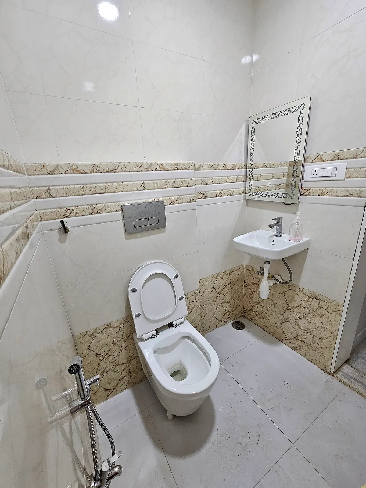 Tiled toilet and washbasin area with mirror, health faucet and floor drain