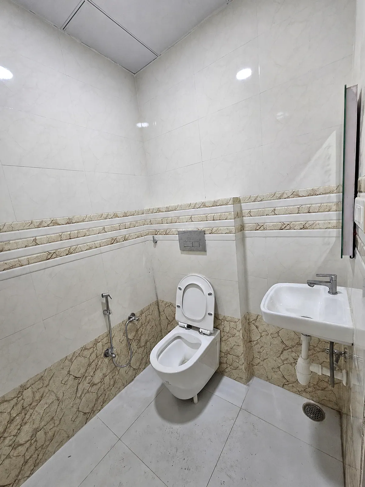 Wider view of the tiled toilet and washbasin area